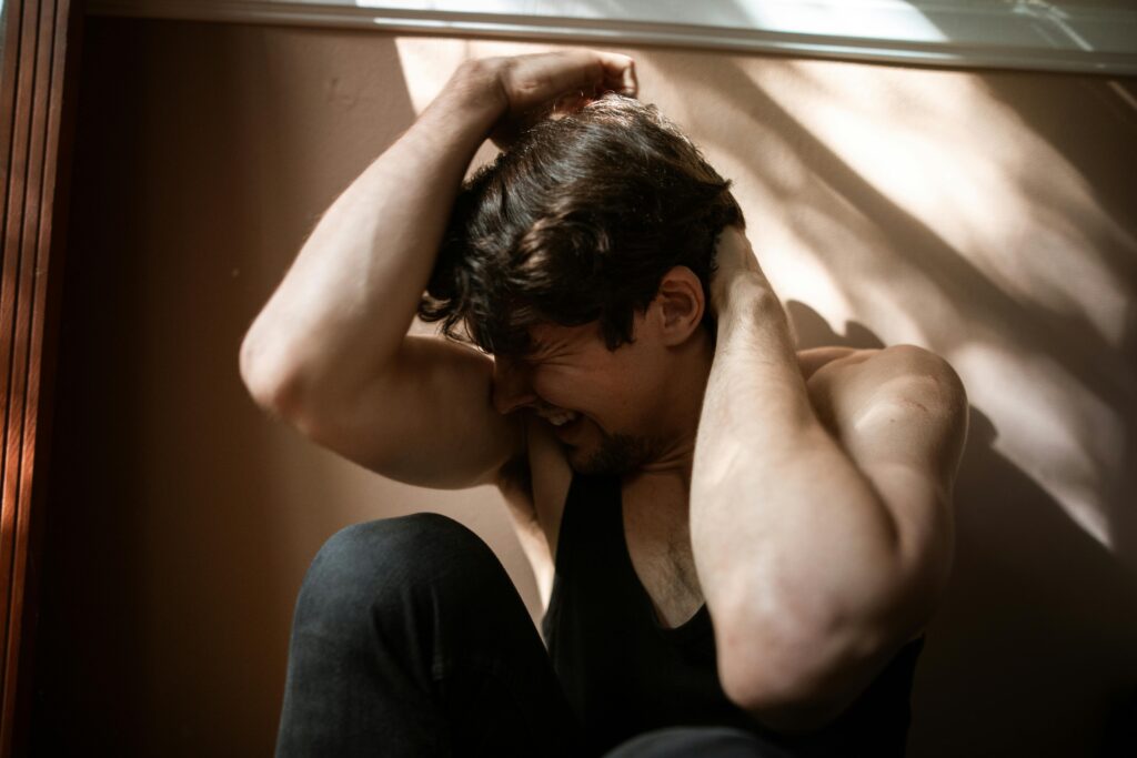 A man experiencing emotional distress in a dimly lit room, symbolizing struggle and mental health.